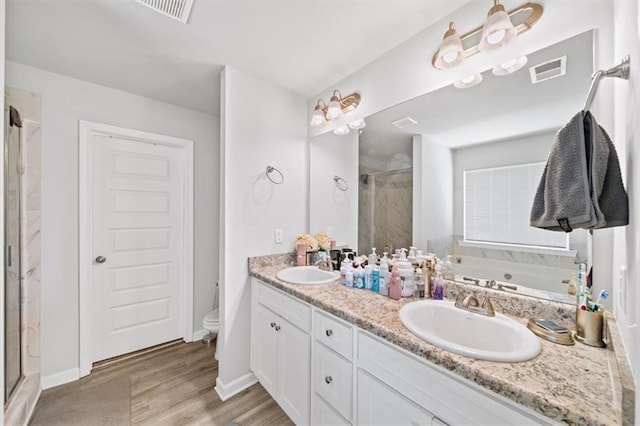 full bath featuring a stall shower, wood finished floors, double vanity, toilet, and a garden tub