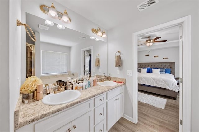 ensuite bathroom with wood finished floors, double vanity, a ceiling fan, and baseboards