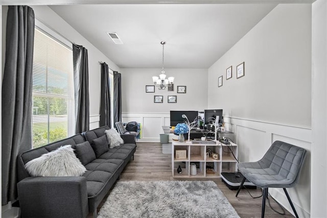 living area featuring a chandelier, wood finished floors, wainscoting, and a decorative wall