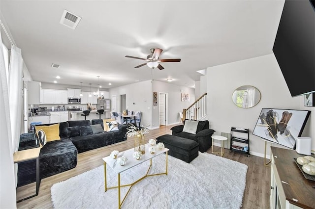 living area featuring stairs, ceiling fan, baseboards, light wood-style floors, and recessed lighting