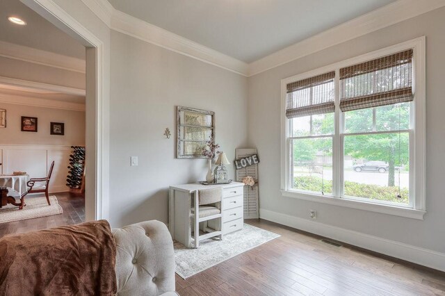 sitting room featuring crown molding, baseboards, light wood-type flooring, and visible vents