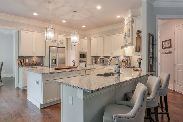 kitchen featuring a peninsula, a kitchen island, a kitchen bar, a sink, and appliances with stainless steel finishes