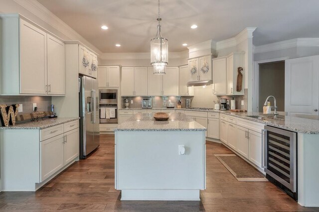 kitchen with decorative backsplash, a kitchen island, a sink, beverage cooler, and stainless steel appliances