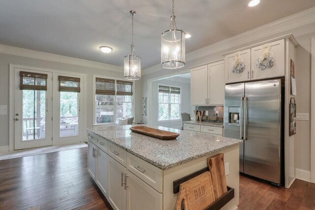 kitchen with stainless steel fridge, white cabinetry, crown molding, and light stone countertops