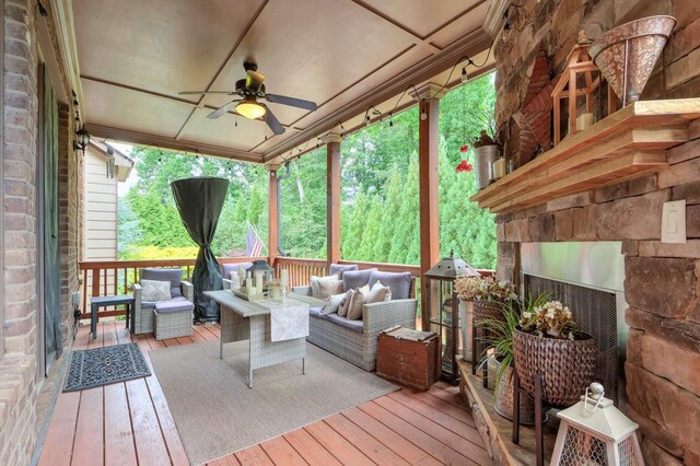 sunroom / solarium featuring ceiling fan, an outdoor living space with a fireplace, and a wealth of natural light