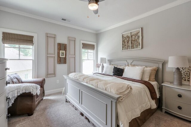 bedroom with ceiling fan, visible vents, baseboards, ornamental molding, and light carpet