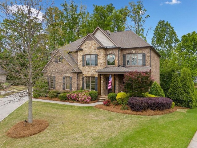 view of front of house with brick siding, a front lawn, and stone siding