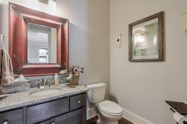half bathroom featuring vanity, baseboards, and toilet