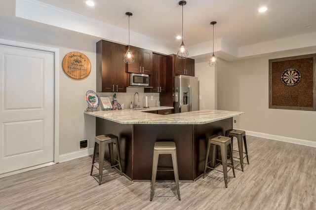 kitchen featuring baseboards, light wood-style flooring, a kitchen breakfast bar, and stainless steel appliances