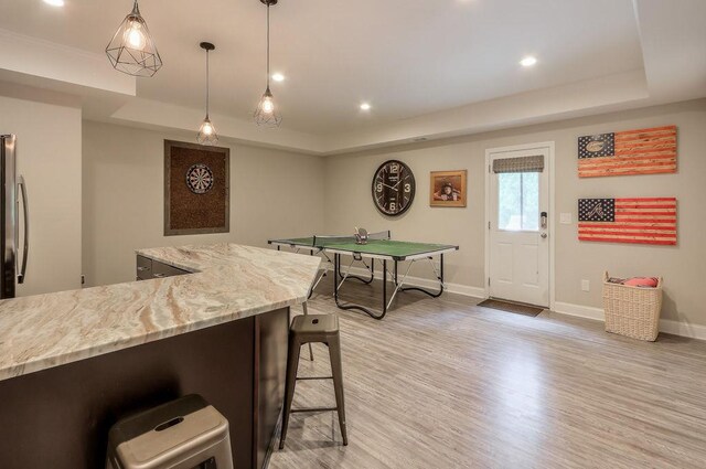 interior space featuring recessed lighting, baseboards, a tray ceiling, and light wood-type flooring