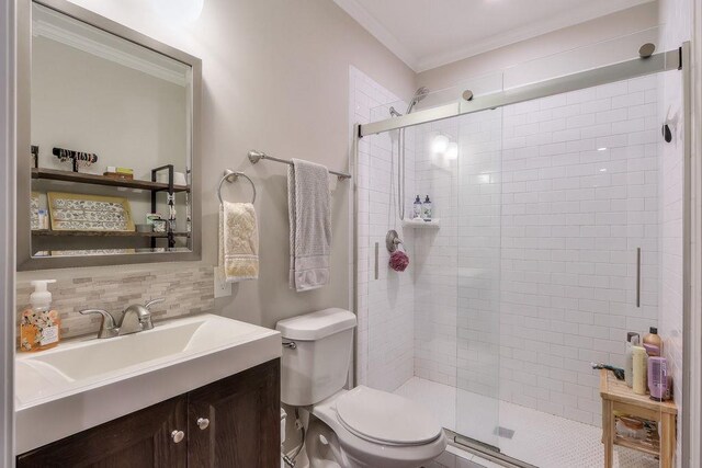 bathroom with decorative backsplash, crown molding, a shower stall, vanity, and toilet