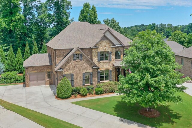 craftsman-style house featuring an attached garage, driveway, a front lawn, and brick siding