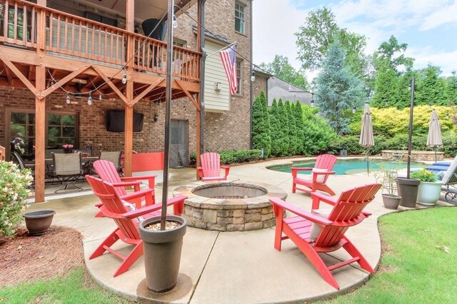 view of patio with an outdoor fire pit, an outdoor pool, and a balcony