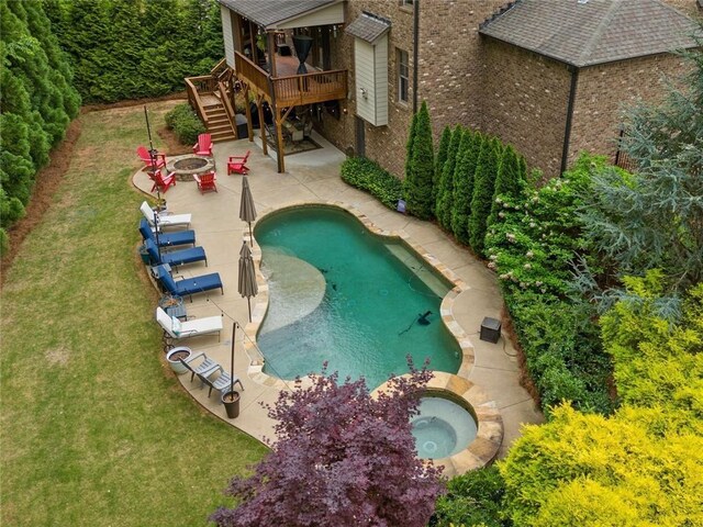 pool featuring an in ground hot tub, a wooden deck, stairway, an outdoor fire pit, and a patio