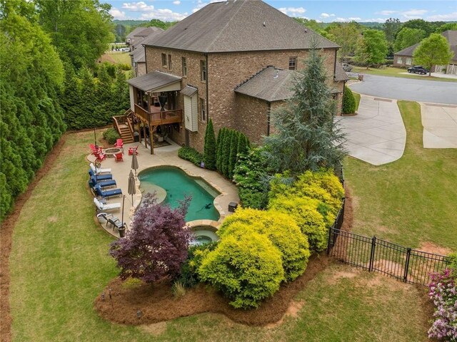 rear view of property with brick siding, a wooden deck, stairway, a fenced backyard, and a yard