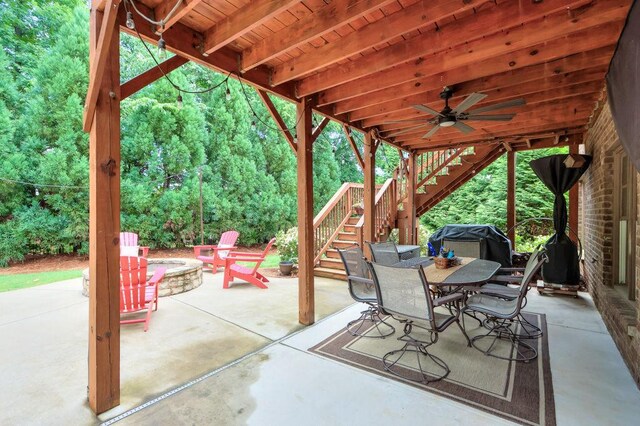 view of patio / terrace with stairs, outdoor dining area, a ceiling fan, and a fire pit