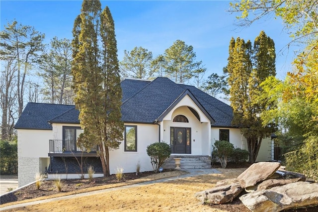 view of front of house featuring roof with shingles and stucco siding