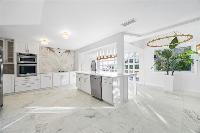 kitchen with visible vents, an island with sink, stainless steel appliances, light countertops, and white cabinetry