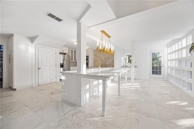 kitchen with visible vents, a breakfast bar area, decorative light fixtures, a peninsula, and light countertops