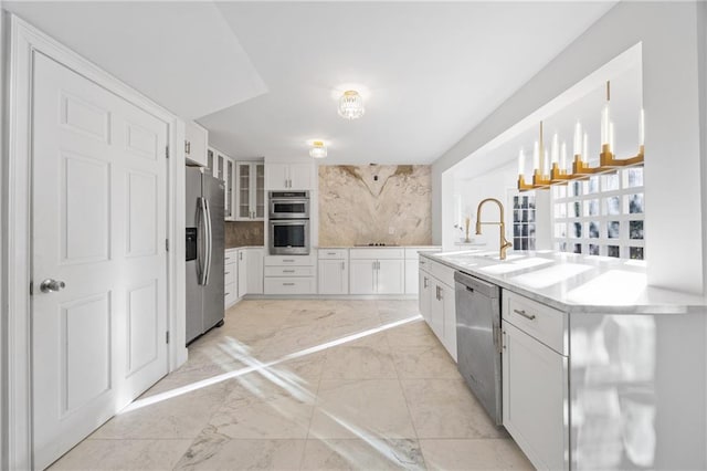 kitchen featuring glass insert cabinets, hanging light fixtures, stainless steel appliances, light countertops, and white cabinetry