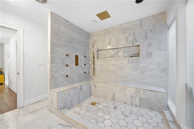 bathroom featuring tiled shower and baseboards