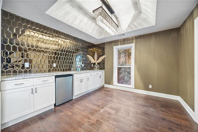 interior space with backsplash, fridge, dark wood finished floors, and white cabinetry