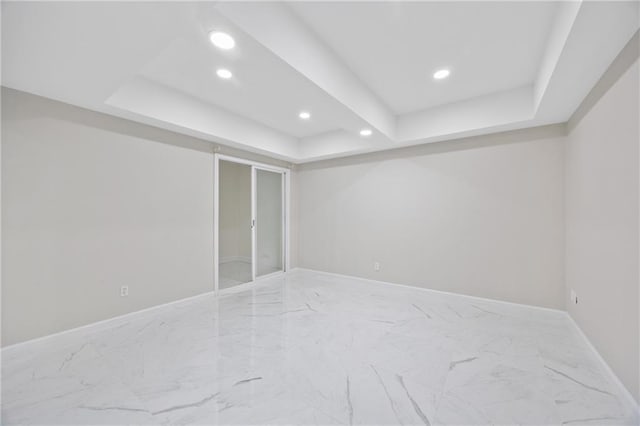 unfurnished room featuring marble finish floor, baseboards, a tray ceiling, and recessed lighting