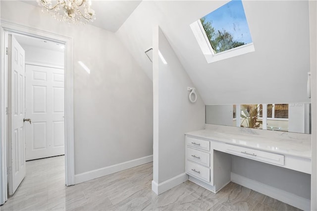 bathroom featuring a chandelier, vaulted ceiling with skylight, vanity, and baseboards