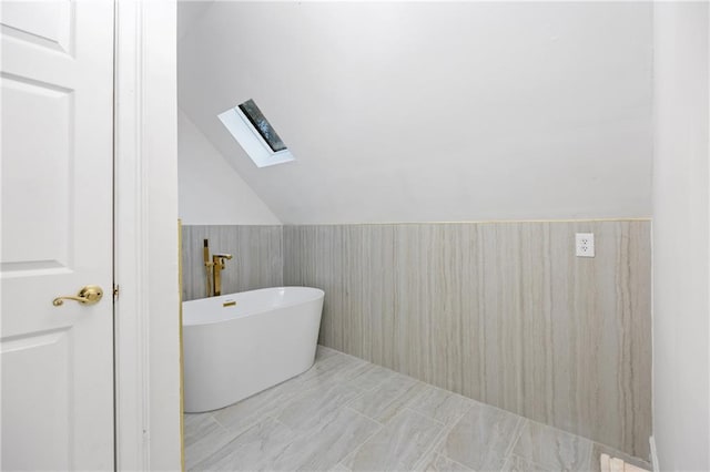 full bath with lofted ceiling with skylight and a freestanding bath