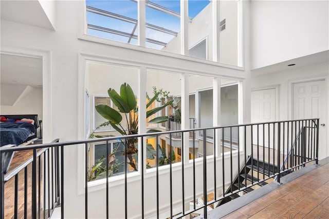 hall featuring a wealth of natural light, a towering ceiling, an upstairs landing, and wood finished floors