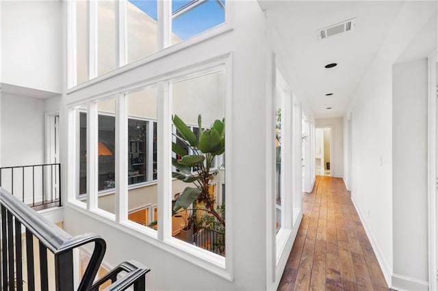 corridor featuring stairs, visible vents, baseboards, and wood finished floors