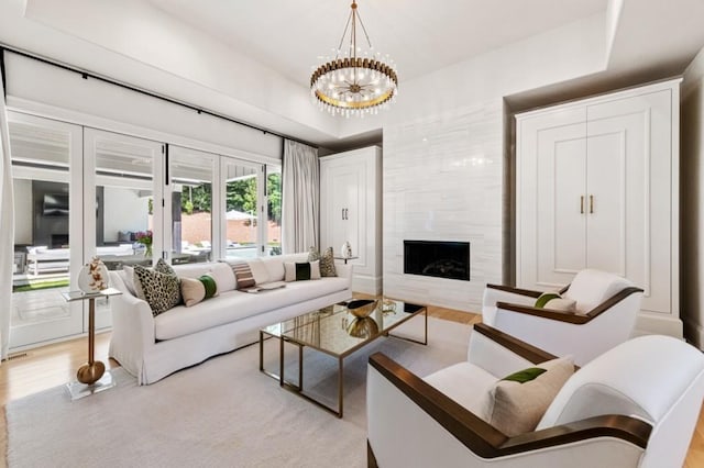 living area featuring light wood finished floors, a premium fireplace, and a chandelier
