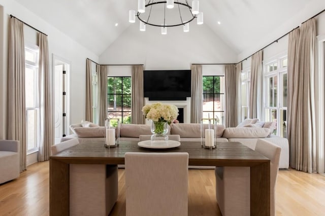 living area with a chandelier, light wood-style flooring, and high vaulted ceiling
