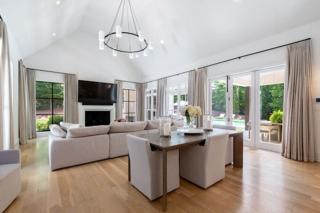 living room featuring a chandelier, high vaulted ceiling, light wood-style floors, and a fireplace