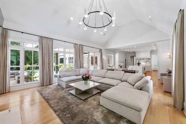 living area with a chandelier, high vaulted ceiling, light wood-style floors, and recessed lighting