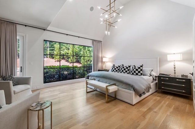 bedroom with light wood-style floors, multiple windows, a chandelier, and a high ceiling