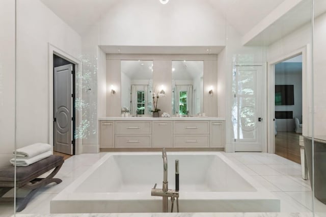 bathroom featuring vaulted ceiling, a bath, and vanity