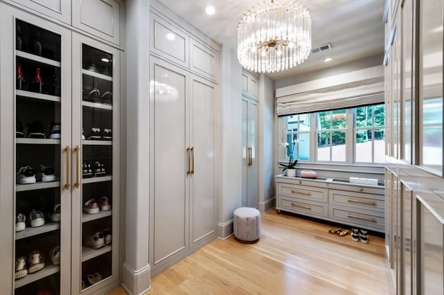 walk in closet with light wood-type flooring and a chandelier