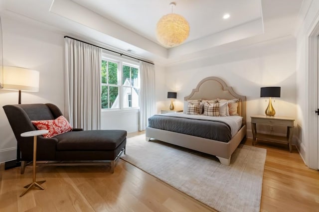 bedroom featuring a tray ceiling, wood finished floors, baseboards, and recessed lighting