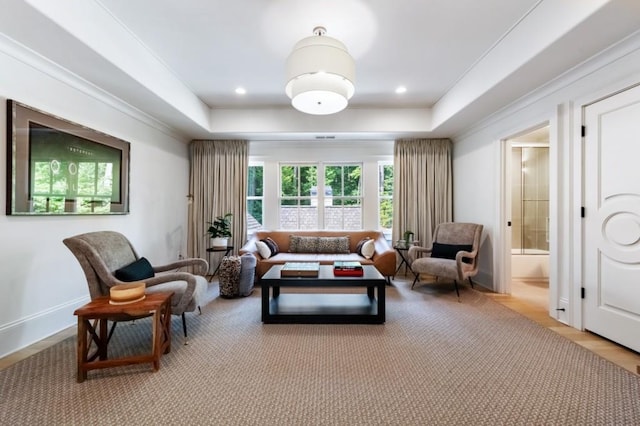 living area with a raised ceiling, crown molding, light wood-style flooring, and baseboards