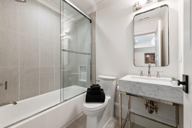 bathroom with toilet, bath / shower combo with glass door, tile patterned floors, and a sink
