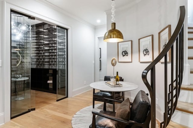 dining area featuring light wood-type flooring, stairs, ornamental molding, and baseboards