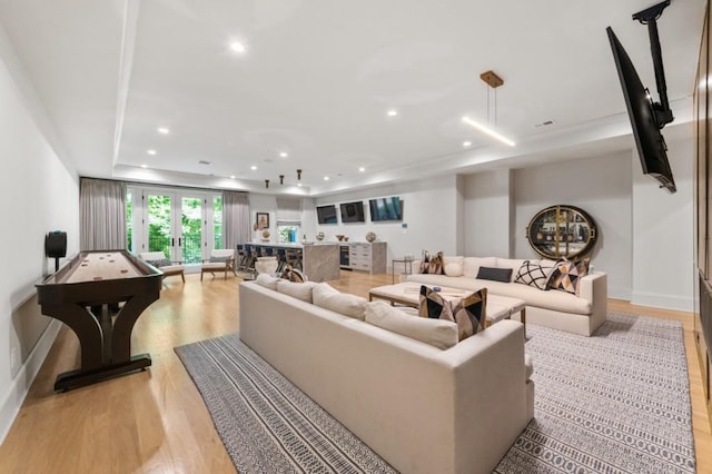 living area featuring a tray ceiling, light wood finished floors, and recessed lighting
