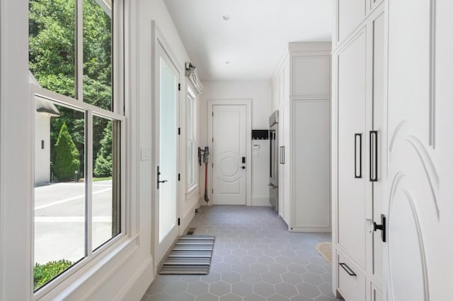 hallway featuring plenty of natural light, baseboards, and light tile patterned floors
