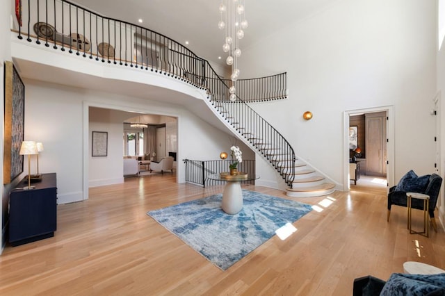 foyer entrance with a high ceiling, wood finished floors, stairway, baseboards, and recessed lighting