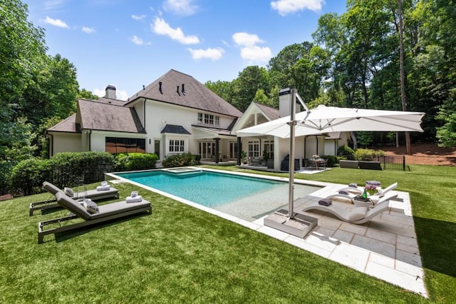 outdoor pool with a patio area and a yard