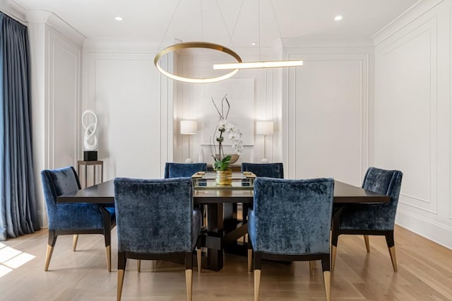 dining room with a decorative wall, light wood-style floors, crown molding, and recessed lighting