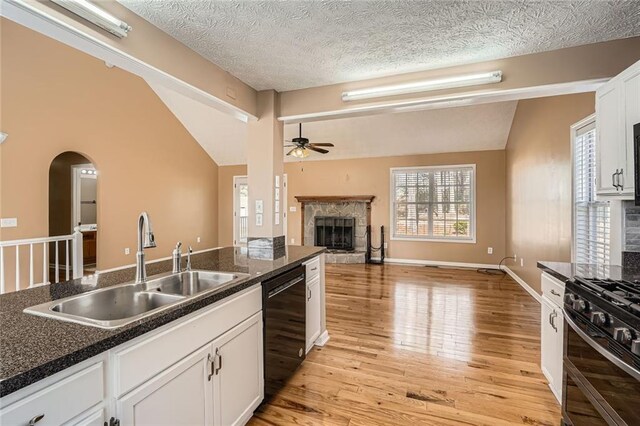 kitchen featuring white cabinets, a textured ceiling, light wood-type flooring, and black appliances