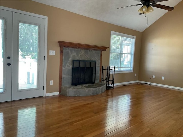 unfurnished living room featuring wood-type flooring, a stone fireplace, vaulted ceiling, and ceiling fan