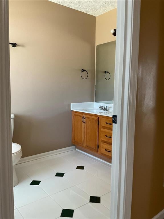 bathroom with a textured ceiling, vanity, toilet, and tile patterned floors